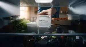 Hand reaching for expired food in a cluttered refrigerator.